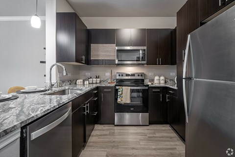 A modern kitchen with dark wood cabinets and stainless steel appliances.