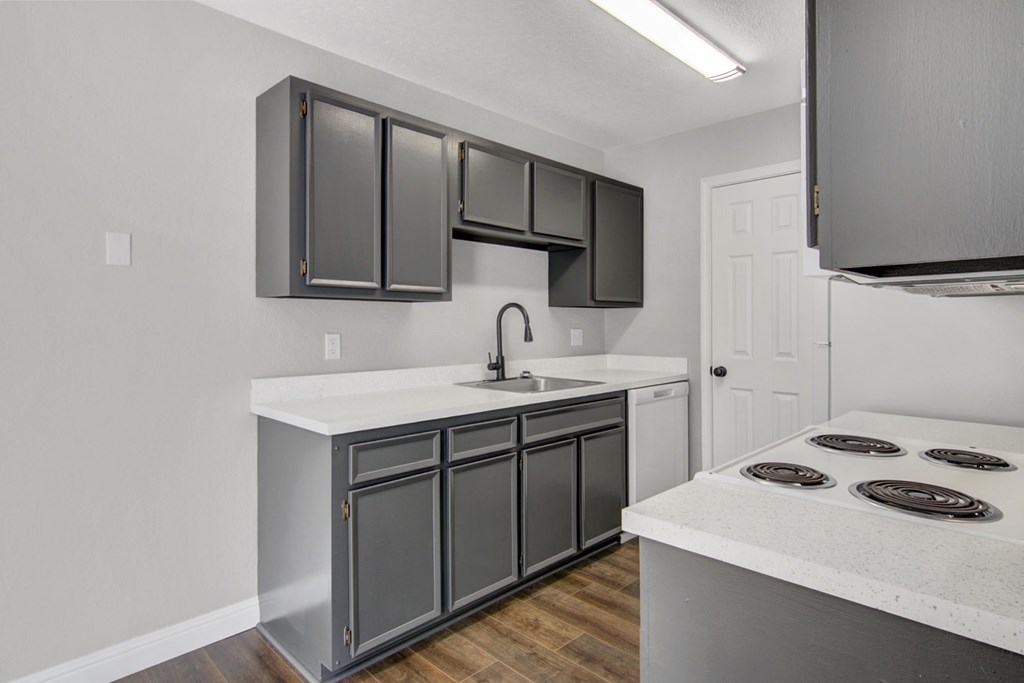 A kitchen with a white countertop and grey cabinets.