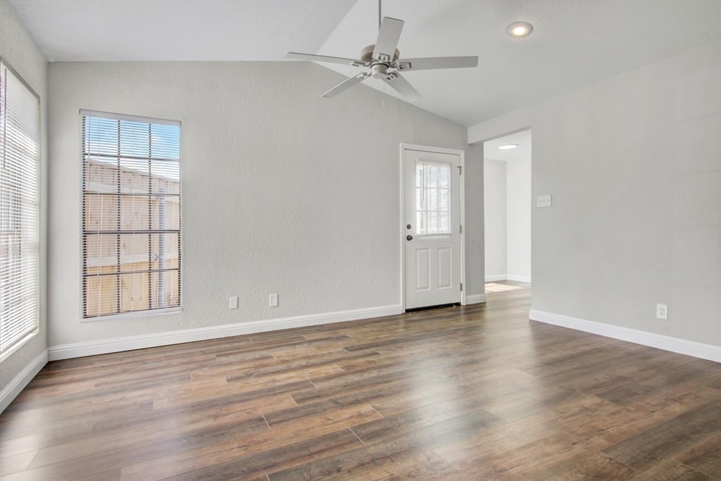 A room with a ceiling fan and wooden flooring.