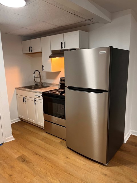 A kitchen with a stainless steel refrigerator and white cabinets.