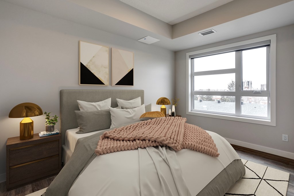 A bedroom with a large bed, a nightstand with a lamp, and a window showing an outdoor view.
