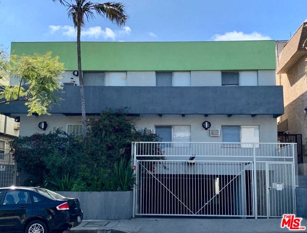 A black car is parked in front of a house with a green roof.