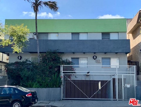 A black car is parked in front of a house with a green roof.