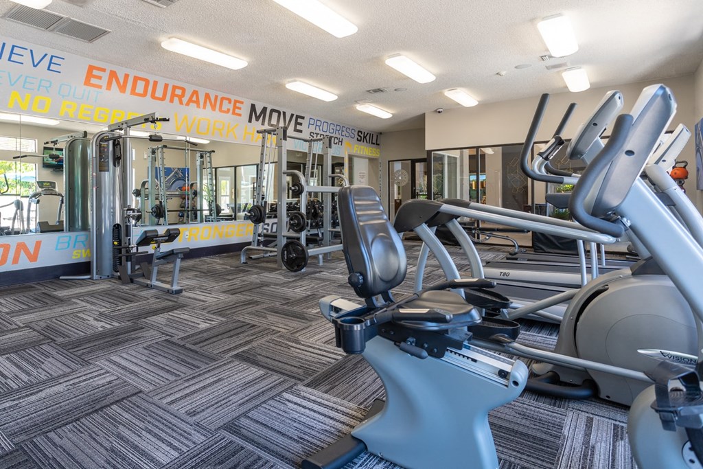 A gym with a variety of equipment including treadmills, weights, and exercise machines.
