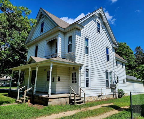 A white two-story house with a porch.