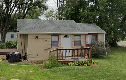 A small house with a brown roof and a red door.