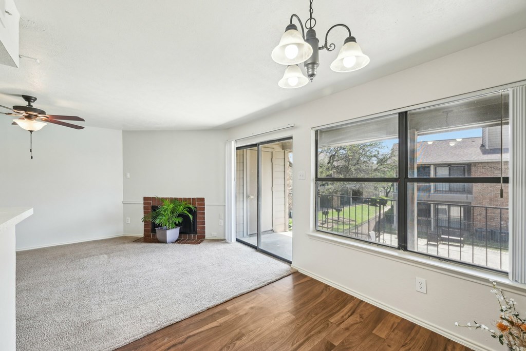 A room with a wooden floor and a window with a view of a fence and grass.
