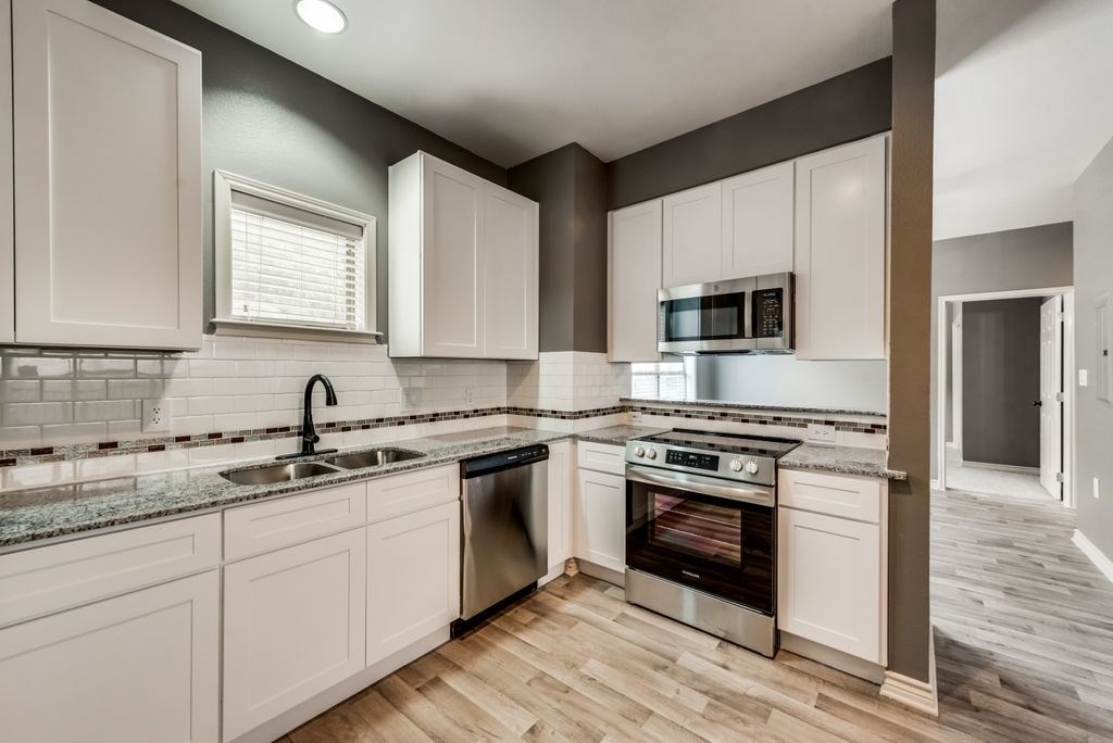A kitchen with white cabinets and a granite countertop.