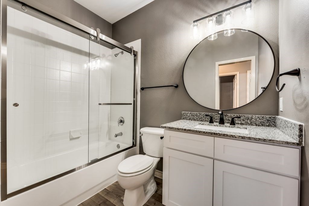 A bathroom with a toilet, sink, and mirror.