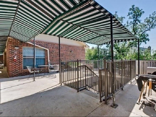 A patio with a black metal railing and a striped awning.