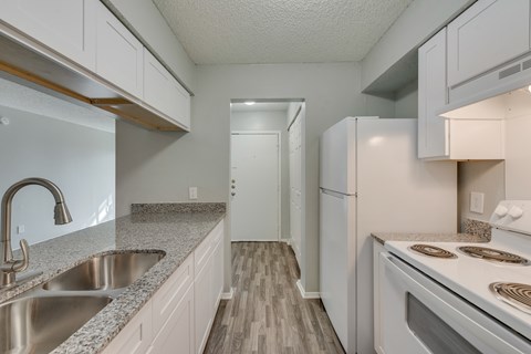 A kitchen with white cabinets and a stainless steel sink.