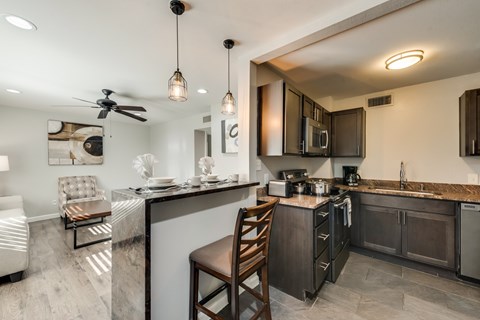 A modern kitchen with dark wood cabinets and a marble countertop.