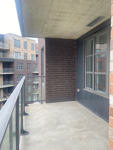 A balcony with a glass railing and a brick wall.