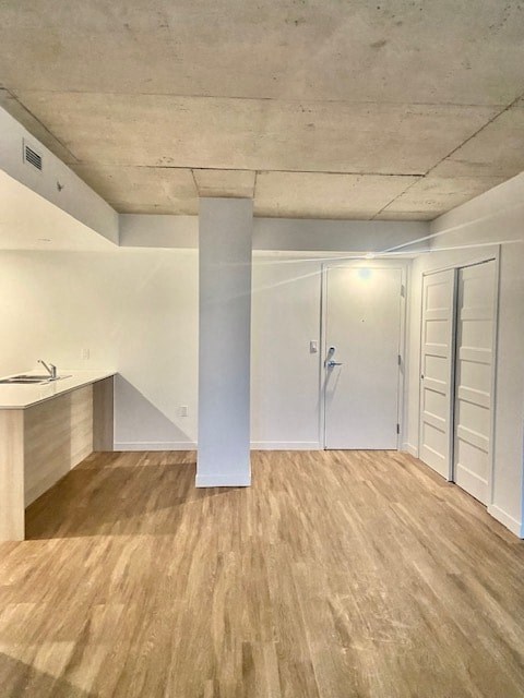 A room with a white column and wooden flooring.