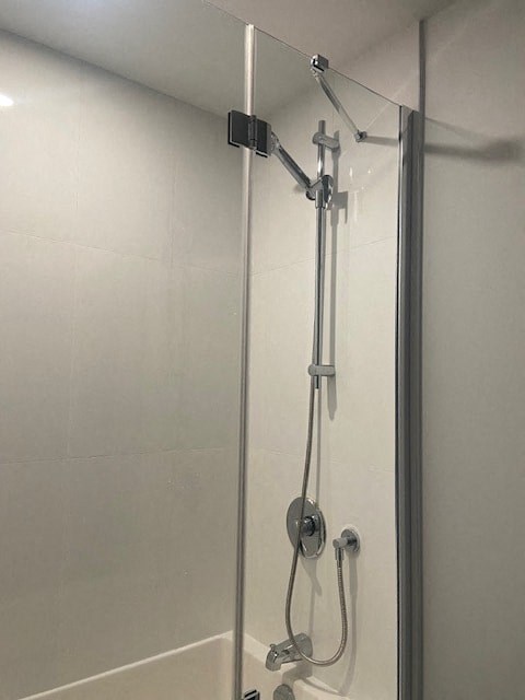 A shower with a glass door and a hand held shower head.