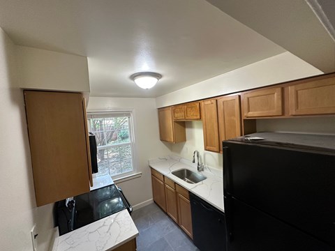 A kitchen with black appliances and wooden cabinets.