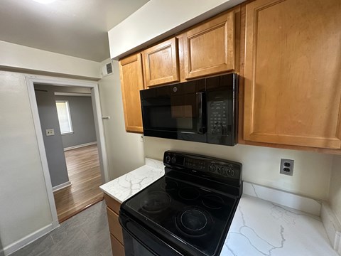 A black microwave is mounted above a black stove in a kitchen.