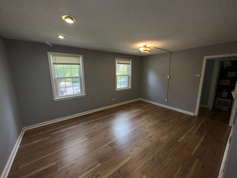 A room with wooden floors and two windows.