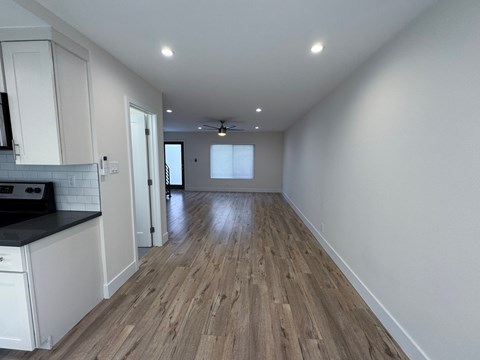 A kitchen with white cabinets and a black countertop with a wood floor.