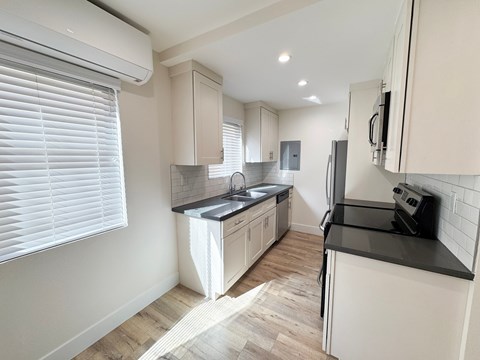 A kitchen with white cabinets and a black countertop.