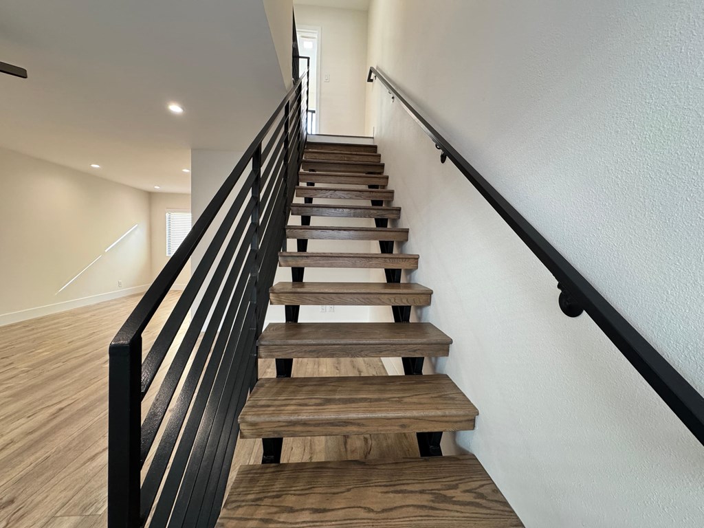 A wooden staircase with a black railing.