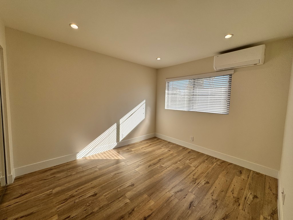 A room with wooden flooring and a window with blinds.