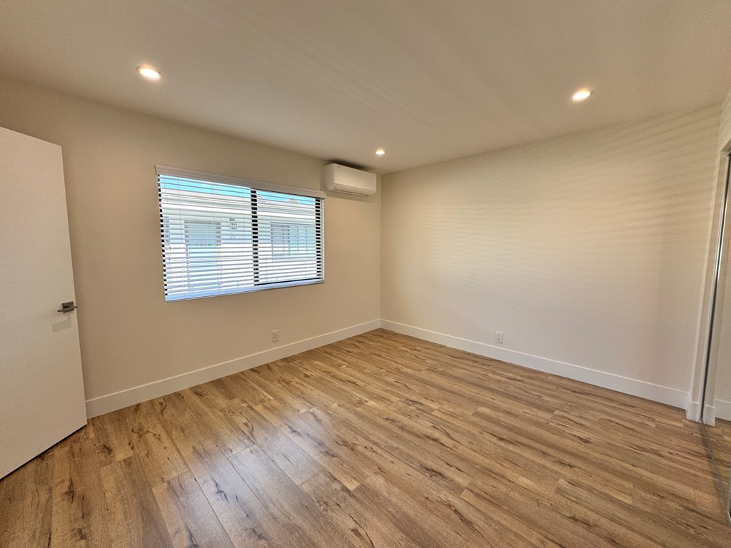 A room with wooden flooring and a window with blinds.