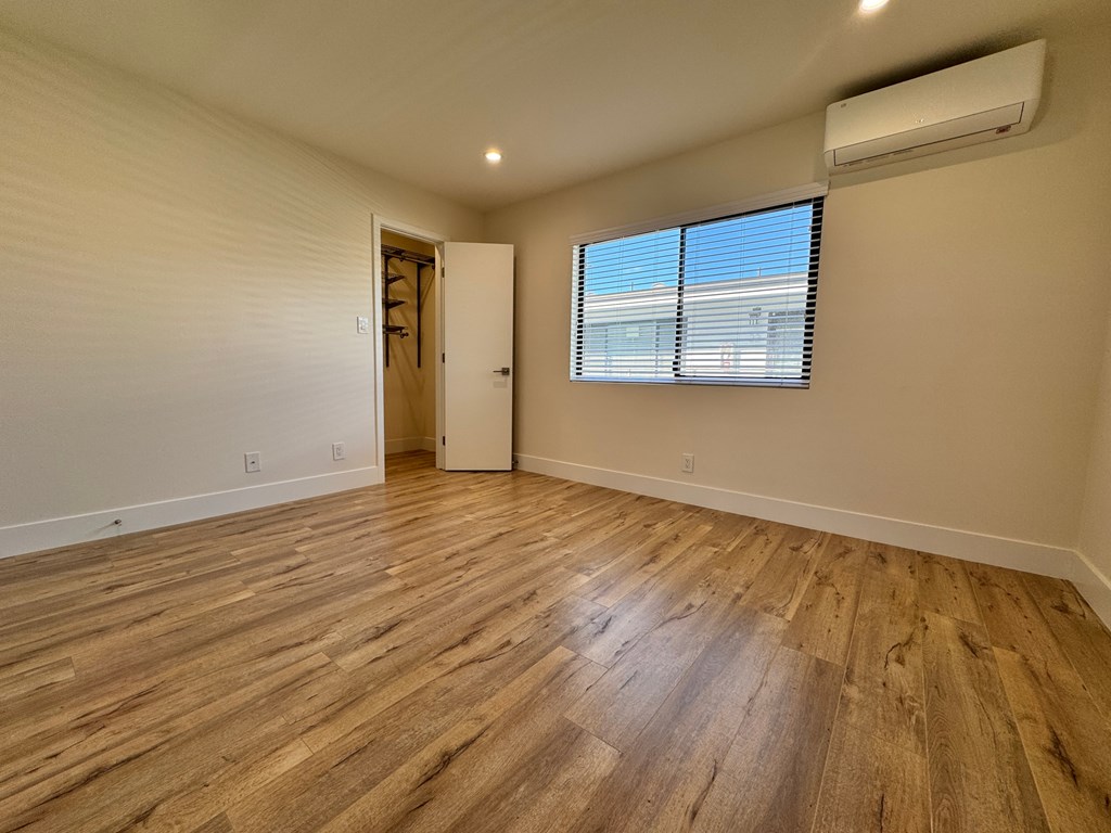 A room with wooden flooring and a window with blinds.