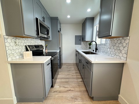 A kitchen with grey cabinets and a white tile backsplash.