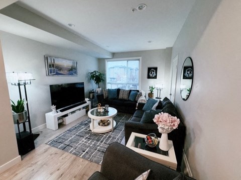 A living room with a grey couch, a white coffee table, and a painting on the wall.