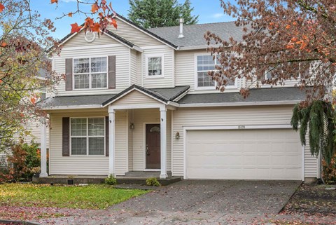 A two-story house with a white garage door and a brown roof.