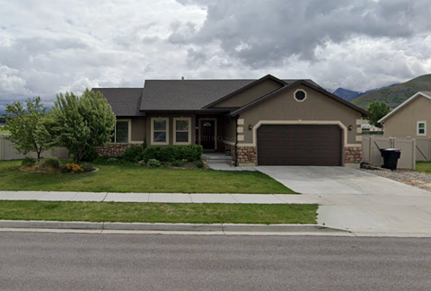 A house with a grey garage door and a brown roof.