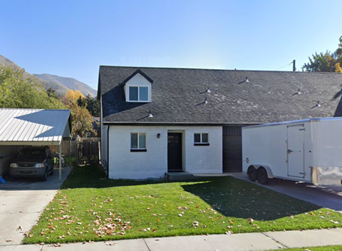 A white house with a grey roof and a black door.