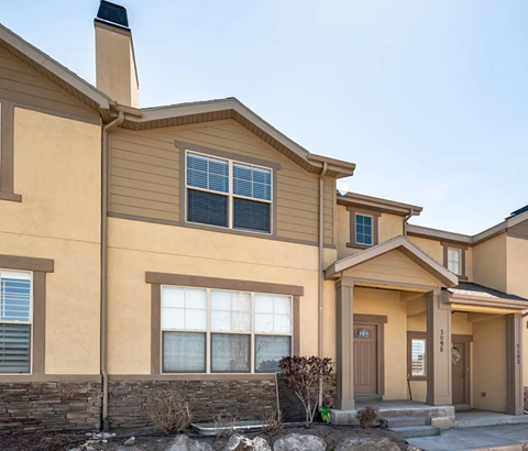 A beige house with a brown door and a small front yard.