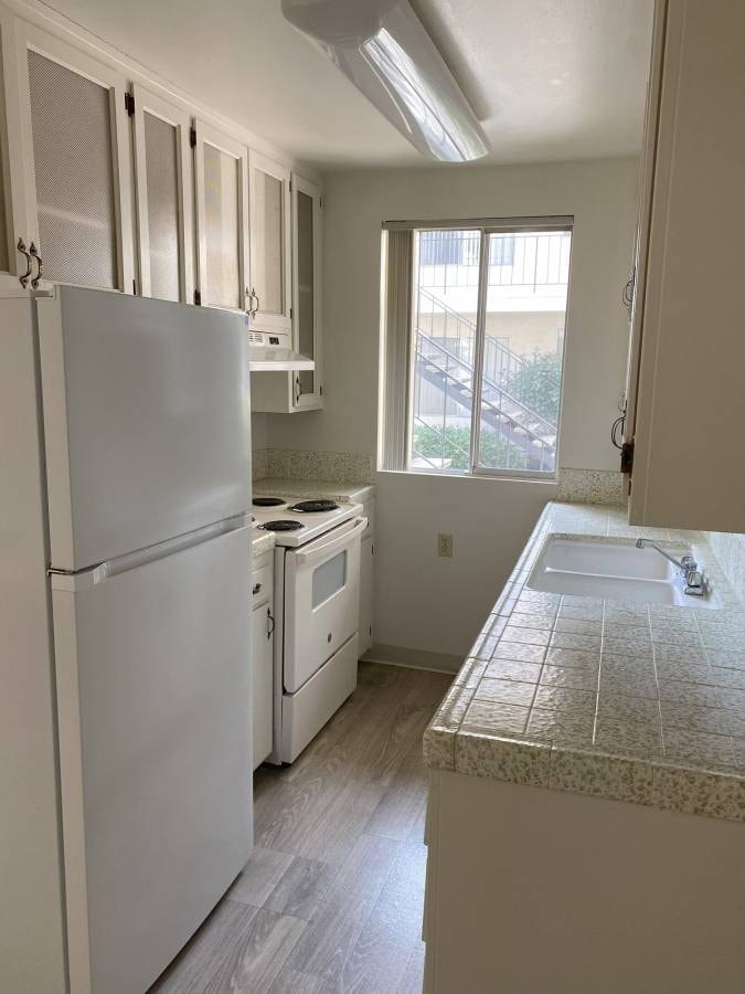A kitchen with a white refrigerator, oven, and sink.