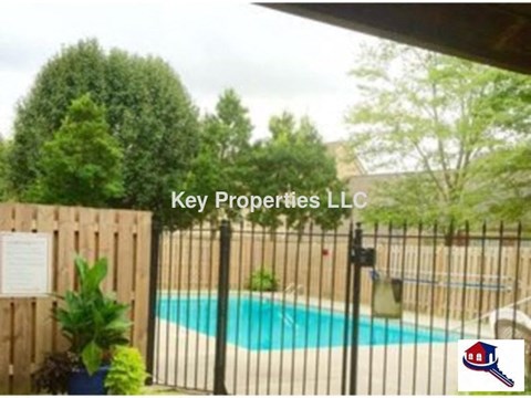 A pool surrounded by a fence with a sign that says Key Properties LLC.