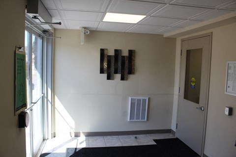 A hallway with a black mat on the floor and a door on the right.