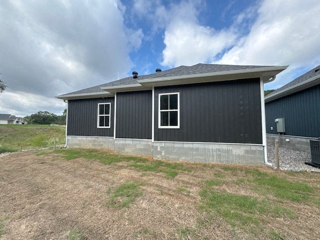 A grey building with a black roof and two windows.