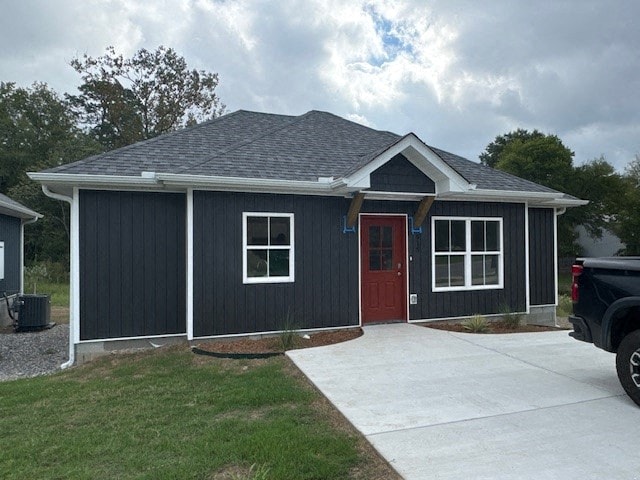 A black house with a red door and a grey roof.