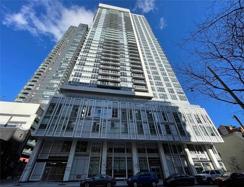 A tall building with a glass facade stands under a blue sky.