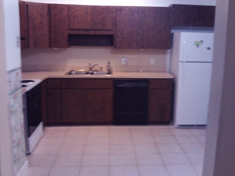 A kitchen with brown cabinets and a white fridge.