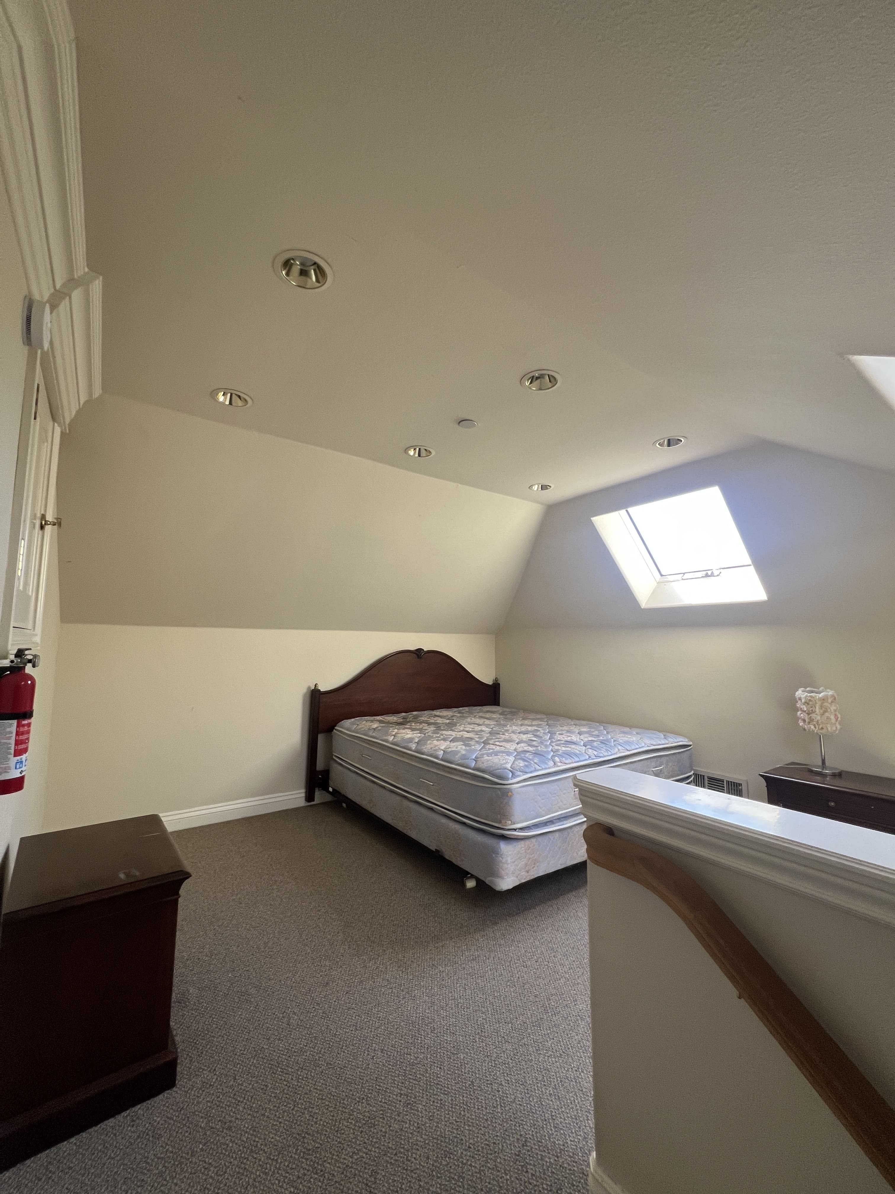 A bedroom with a bed, nightstand, and window.