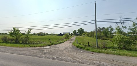 A dirt road leads to a building in the distance.