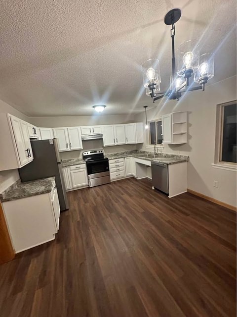 A kitchen with white cabinets and a black fridge.