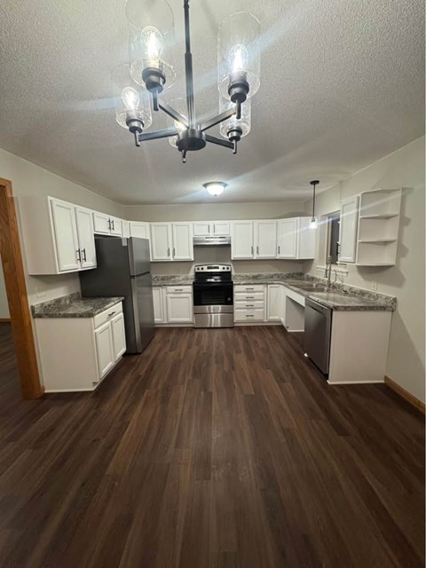 A kitchen with white cabinets and a black fridge.