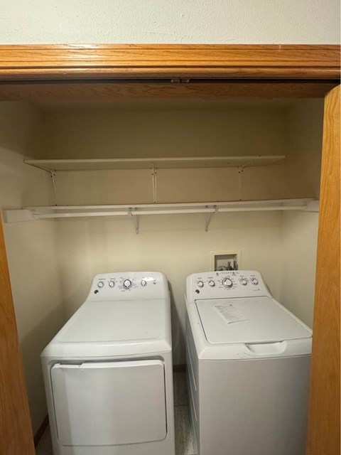 Two white front load washing machines in a small laundry room.