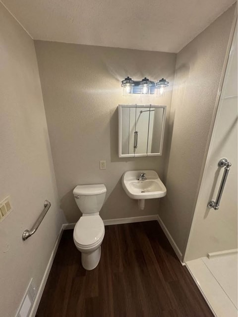 A small bathroom with a toilet, sink and mirror.