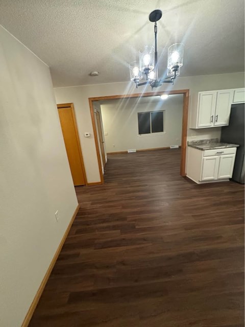 A kitchen with white cabinets and a black fridge is visible.