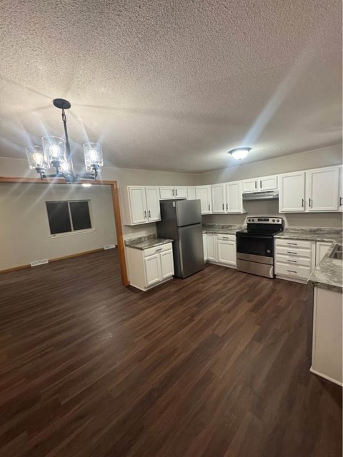 A kitchen with white cabinets and a wooden floor.
