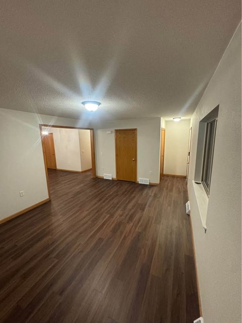 A long hallway with wooden floors and white walls.